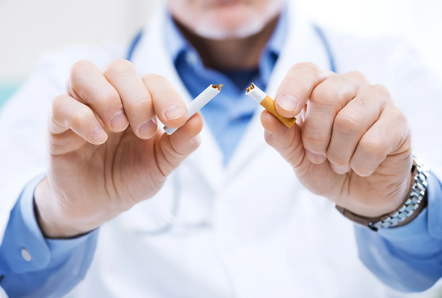 A healthcare professional holding a broken cigarette, representing medical advice about stopping smoking