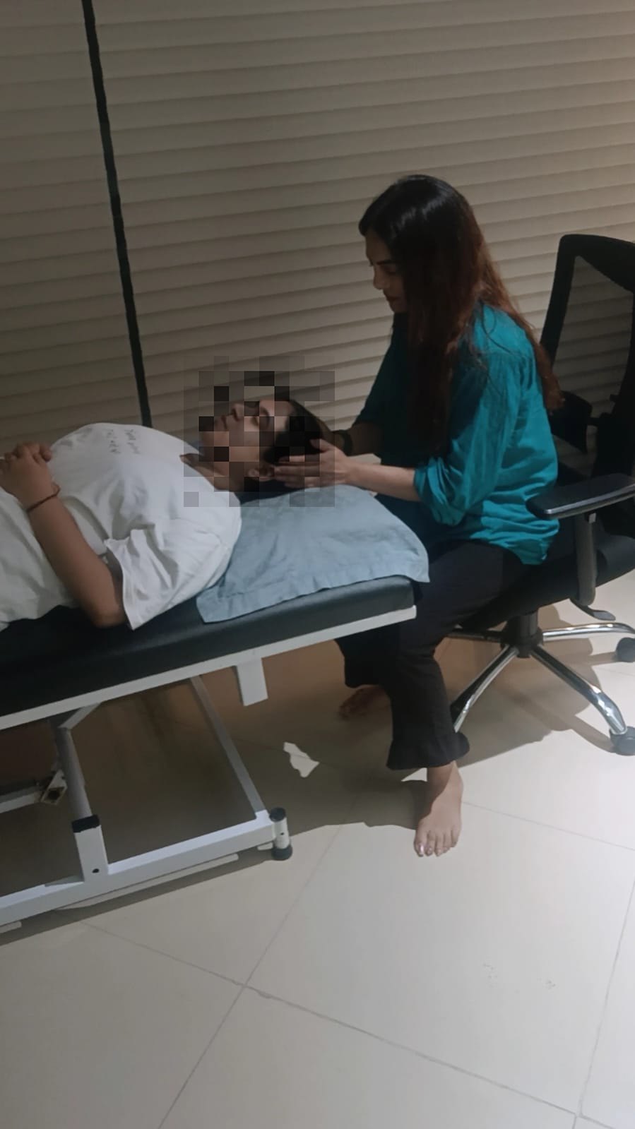 A client resting comfortably during a supportive hypnotherapy session with the practitioner nearby