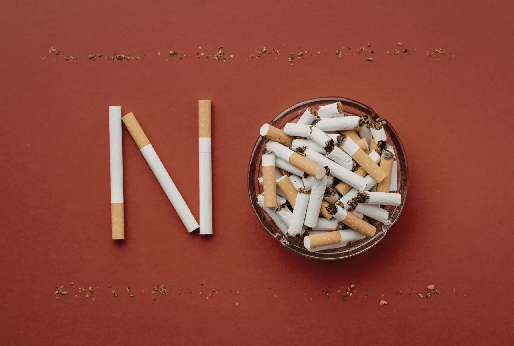Cigarettes arranged to spell the word no beside a full ashtray, representing the decision to stop smoking